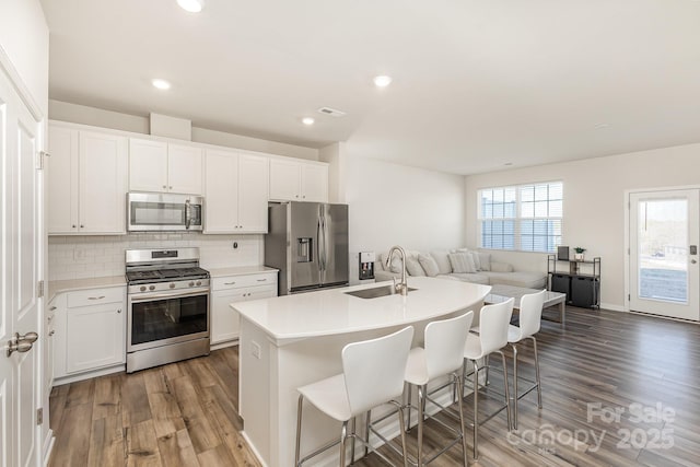 6048 Chelsea Oaks Rdg, Tega Cay, SC 29708 - kitchen featuring appliances with stainless steel finishes, a sink, light wood-type flooring, a breakfast bar, and tasteful backsplash