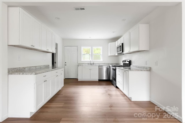 2694 W Lakeshore Dr, Landrum, SC 29356 - kitchen with appliances with stainless steel finishes, light wood-style flooring, a sink, light countertops, and white cabinetry