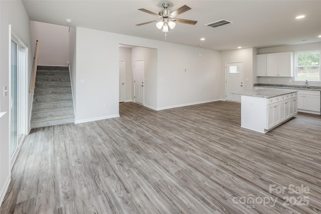 kitchen with open floor plan, visible vents, white cabinetry, and light wood-type flooring