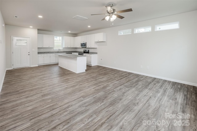 kitchen with a sink, open floor plan, appliances with stainless steel finishes, and a kitchen island