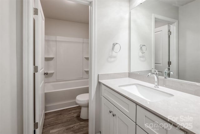bathroom featuring  shower combination, toilet, vanity, and wood finished floors