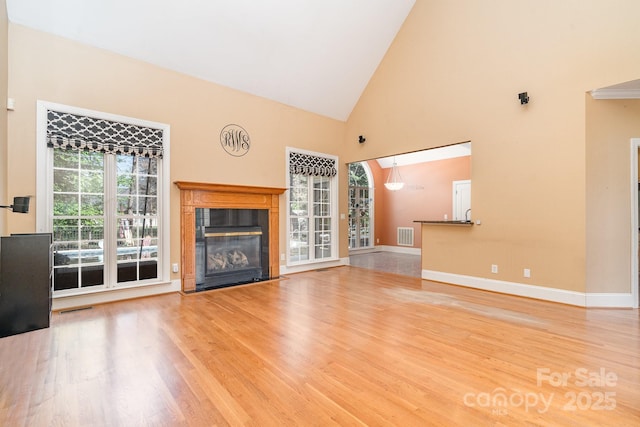 unfurnished living room featuring visible vents, baseboards, wood finished floors, and a premium fireplace