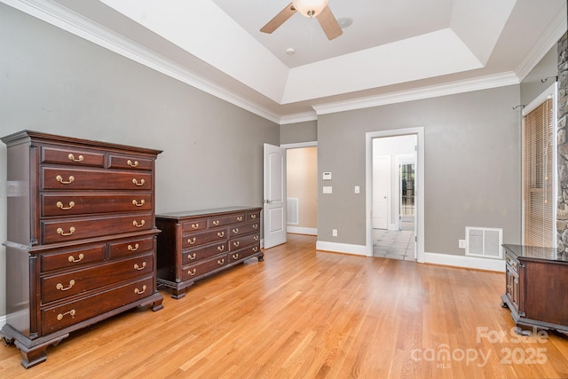 bedroom featuring baseboards, a tray ceiling, light wood finished floors, and visible vents