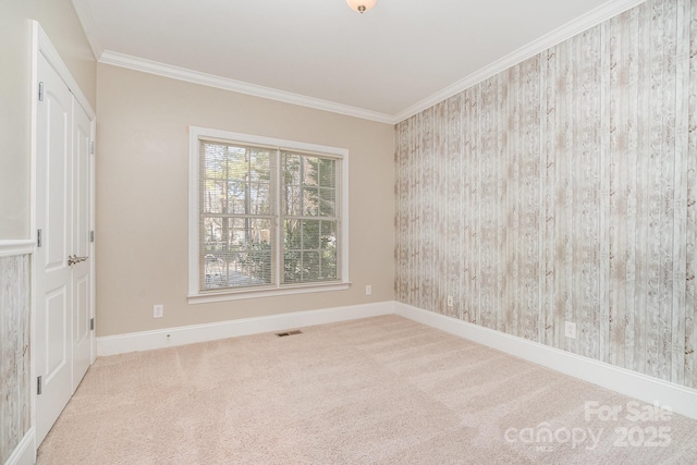 unfurnished bedroom with carpet floors, baseboards, visible vents, and ornamental molding