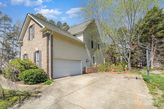 view of home's exterior featuring brick siding, a garage, concrete driveway, and roof with shingles