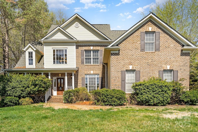view of front of property with french doors, brick siding, a shingled roof, and a front yard