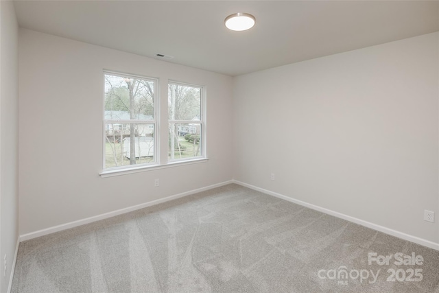 empty room with baseboards, visible vents, and carpet