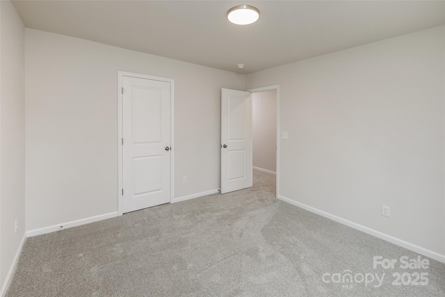 carpeted spare room featuring baseboards
