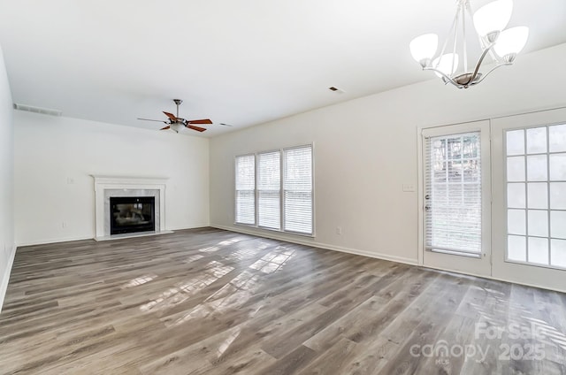 10434 Henbane Ct, Charlotte, NC 28213 - unfurnished living room featuring visible vents, baseboards, wood finished floors, and ceiling fan with notable chandelier