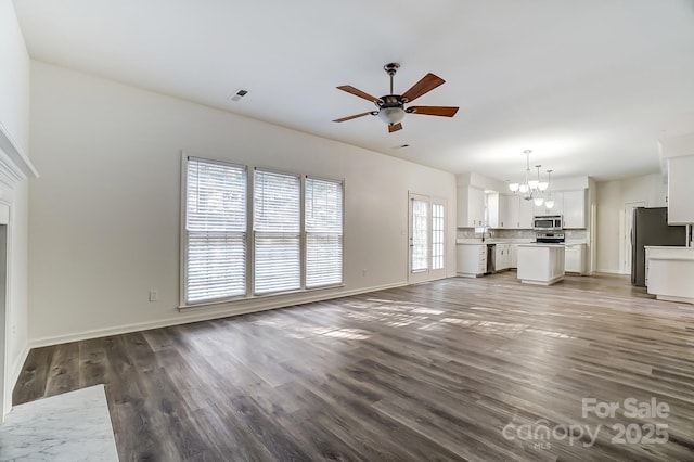 10434 Henbane Ct, Charlotte, NC 28213 - unfurnished living room featuring visible vents, baseboards, ceiling fan with notable chandelier, wood finished floors, and a sink