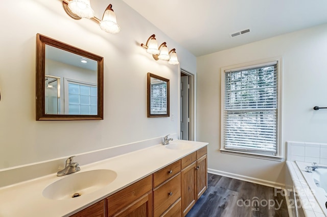 10434 Henbane Ct, Charlotte, NC 28213 - bathroom with double vanity, a relaxing tiled tub, visible vents, and a sink