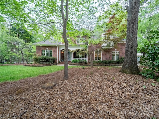 view of front facade with brick siding, a porch, and a front lawn