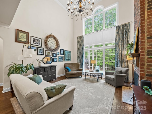 living area with wood finished floors, a high ceiling, baseboards, and an inviting chandelier