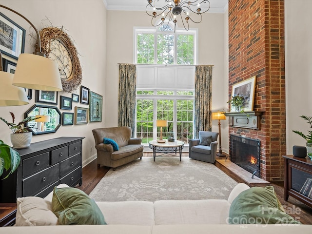 living area with crown molding, a chandelier, a towering ceiling, and a fireplace