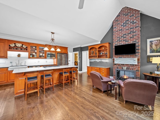living room featuring lofted ceiling, a brick fireplace, and wood finished floors