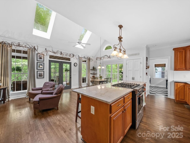 kitchen with high end stainless steel range oven, open floor plan, a kitchen bar, a skylight, and brown cabinets
