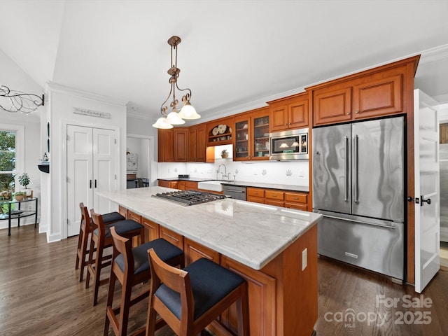 kitchen featuring brown cabinets, a sink, a center island, appliances with stainless steel finishes, and dark wood-style flooring