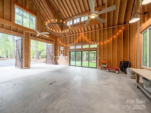misc room with high vaulted ceiling, concrete flooring, and a healthy amount of sunlight