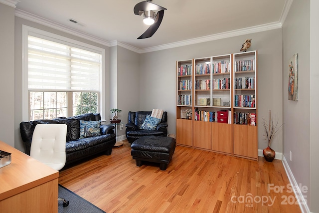 office with baseboards, visible vents, light wood-style floors, and crown molding