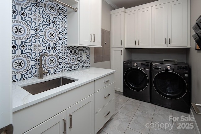 washroom with cabinet space, ornamental molding, a sink, and washer and dryer