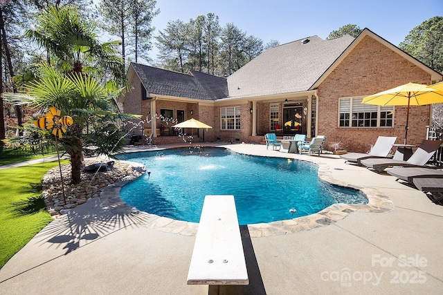 pool with a diving board and a patio