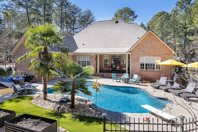 outdoor pool featuring fence, a patio, a garden, and a diving board