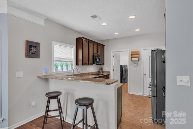 1017 Chalk Hill Ln, Charlotte, NC 28214 - kitchen featuring a kitchen breakfast bar, a textured ceiling, a peninsula, recessed lighting, and independent washer and dryer