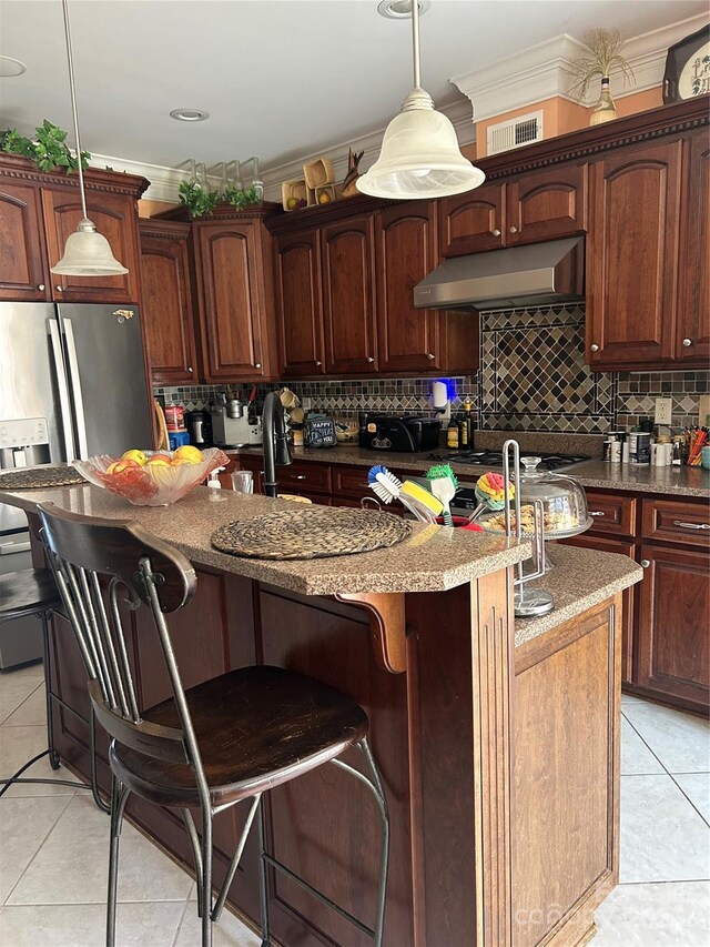 1308 Moonshadow Ln, Shelby, NC 28150 - kitchen featuring under cabinet range hood, a center island with sink, light tile patterned floors, decorative backsplash, and stainless steel fridge