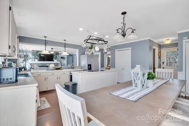 dining area featuring a healthy amount of sunlight, dark wood-style flooring, ornamental molding, and an inviting chandelier