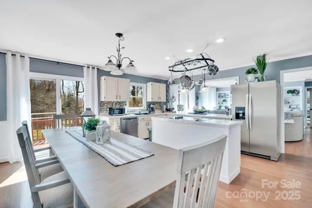 dining area with light wood-style flooring, a notable chandelier, and recessed lighting