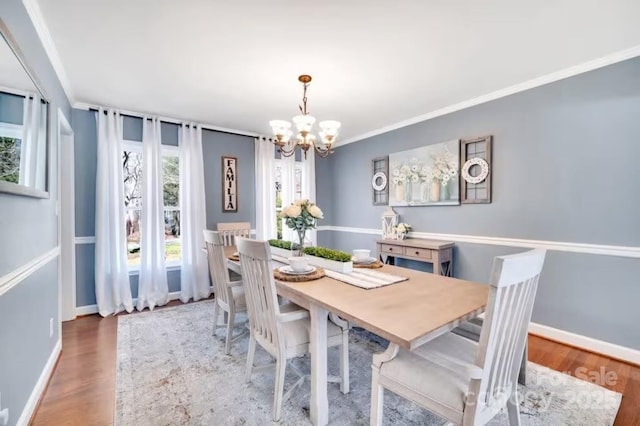 dining area with an inviting chandelier, crown molding, baseboards, and wood finished floors
