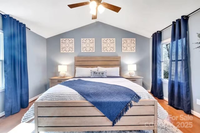 bedroom featuring baseboards, vaulted ceiling, light wood-type flooring, and a ceiling fan