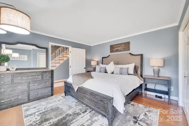 bedroom featuring ornamental molding, baseboards, and wood finished floors