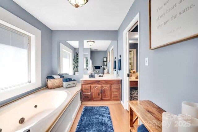 full bath with wood finished floors, vanity, connected bathroom, and a bath