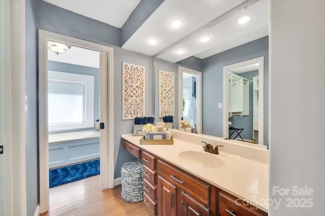 bathroom with wood finished floors, recessed lighting, and vanity
