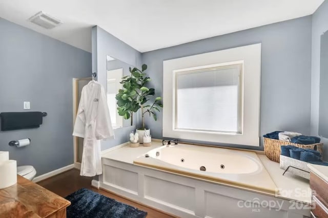 full bath featuring a tub with jets, baseboards, visible vents, and a healthy amount of sunlight