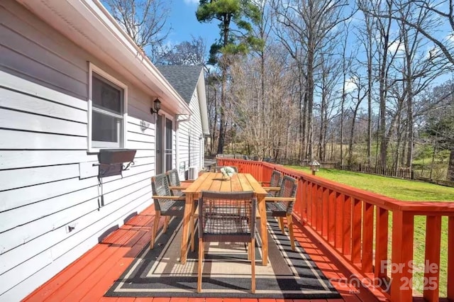 wooden terrace featuring a lawn, outdoor dining area, and fence