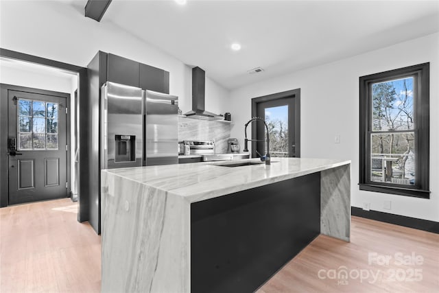 5501 Joyce Dr, Charlotte, NC 28215 - kitchen featuring wall chimney exhaust hood, a sink, modern cabinets, dark cabinetry, and stainless steel appliances