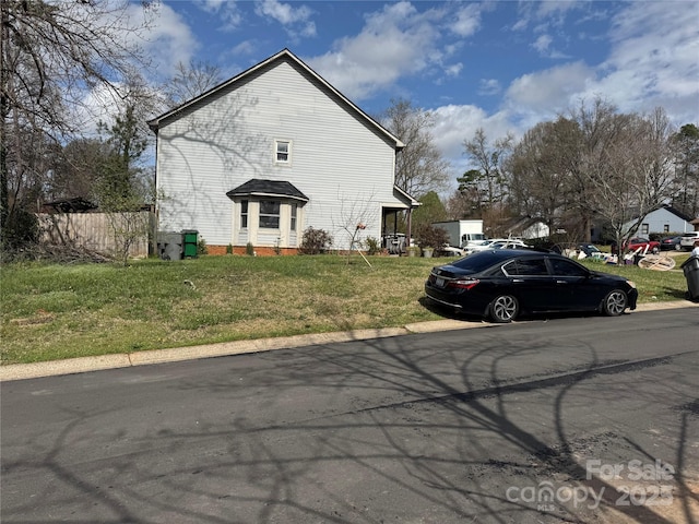 view of property exterior with a lawn and fence