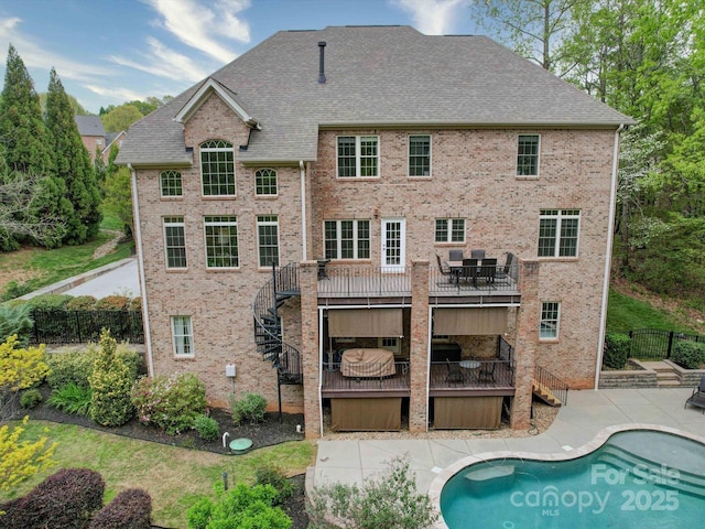 rear view of property featuring fence, stairs, brick siding, a fenced in pool, and a patio area