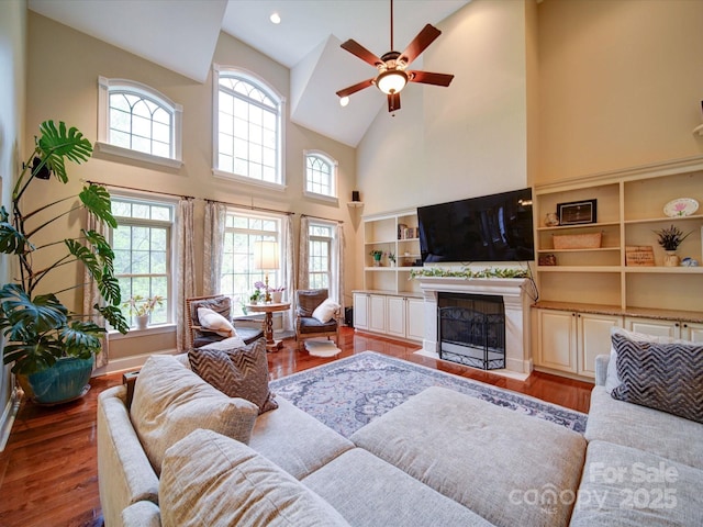 living room featuring a healthy amount of sunlight, high vaulted ceiling, ceiling fan, and wood finished floors
