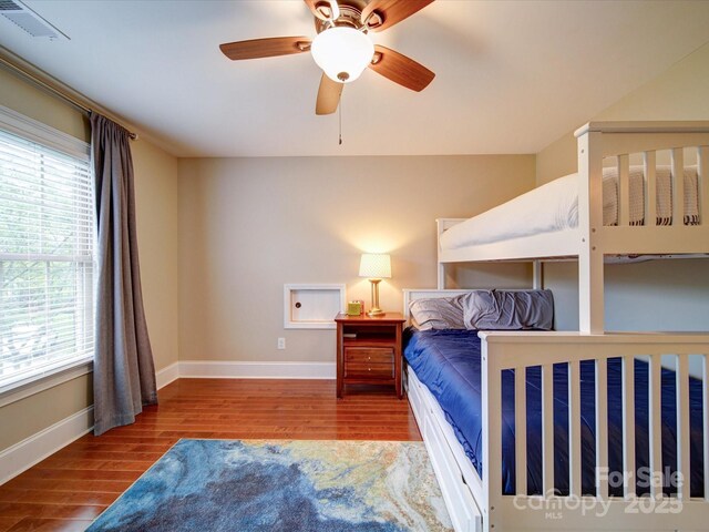 bedroom featuring a ceiling fan, baseboards, visible vents, and wood finished floors