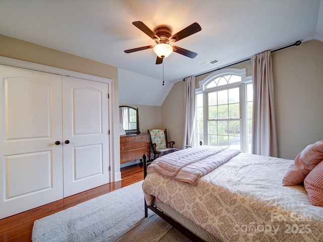 bedroom featuring visible vents, a closet, lofted ceiling, wood finished floors, and ceiling fan