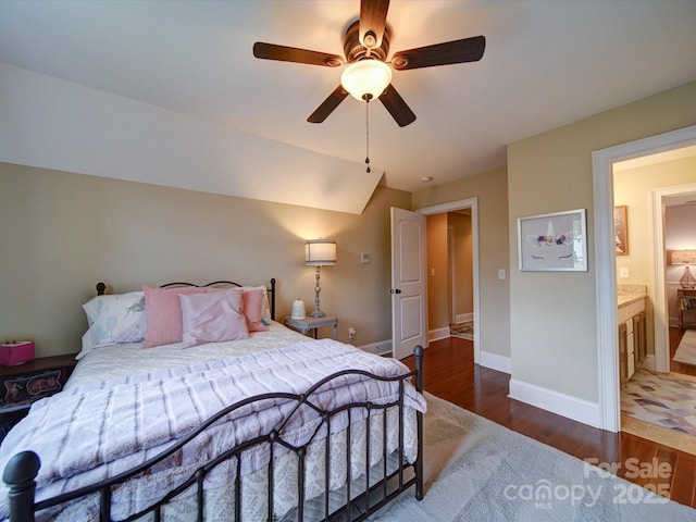 bedroom featuring connected bathroom, ceiling fan, baseboards, wood finished floors, and vaulted ceiling