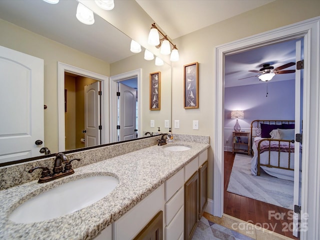 ensuite bathroom featuring connected bathroom, double vanity, a ceiling fan, and a sink