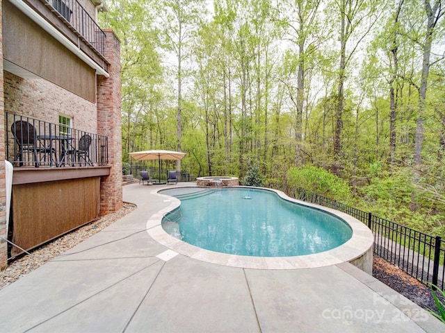 view of pool featuring fence, a fenced in pool, a view of trees, an in ground hot tub, and a patio