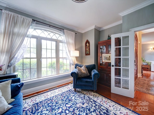 living area featuring crown molding, baseboards, and wood finished floors