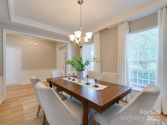 9607 Kestral Ridge Dr, Charlotte, NC 28269 - dining room with a chandelier, light wood-type flooring, a tray ceiling, ornamental molding, and a wainscoted wall