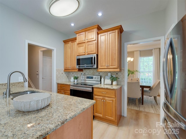 9607 Kestral Ridge Dr, Charlotte, NC 28269 - kitchen featuring stainless steel appliances, a sink, light wood-style flooring, tasteful backsplash, and light stone countertops