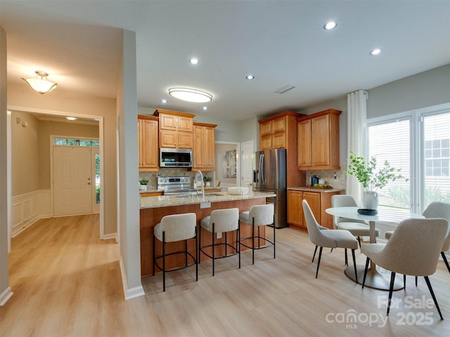 9607 Kestral Ridge Dr, Charlotte, NC 28269 - kitchen with stainless steel appliances, light wood finished floors, tasteful backsplash, recessed lighting, and a wainscoted wall